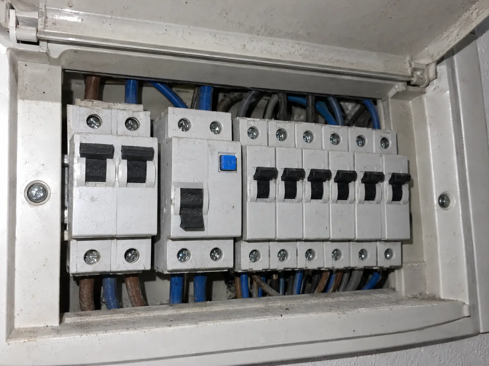Cuadro doméstico abierto con el interruptor general, un diferencial con la palanca bajada y seis magnetotérmicos subidos